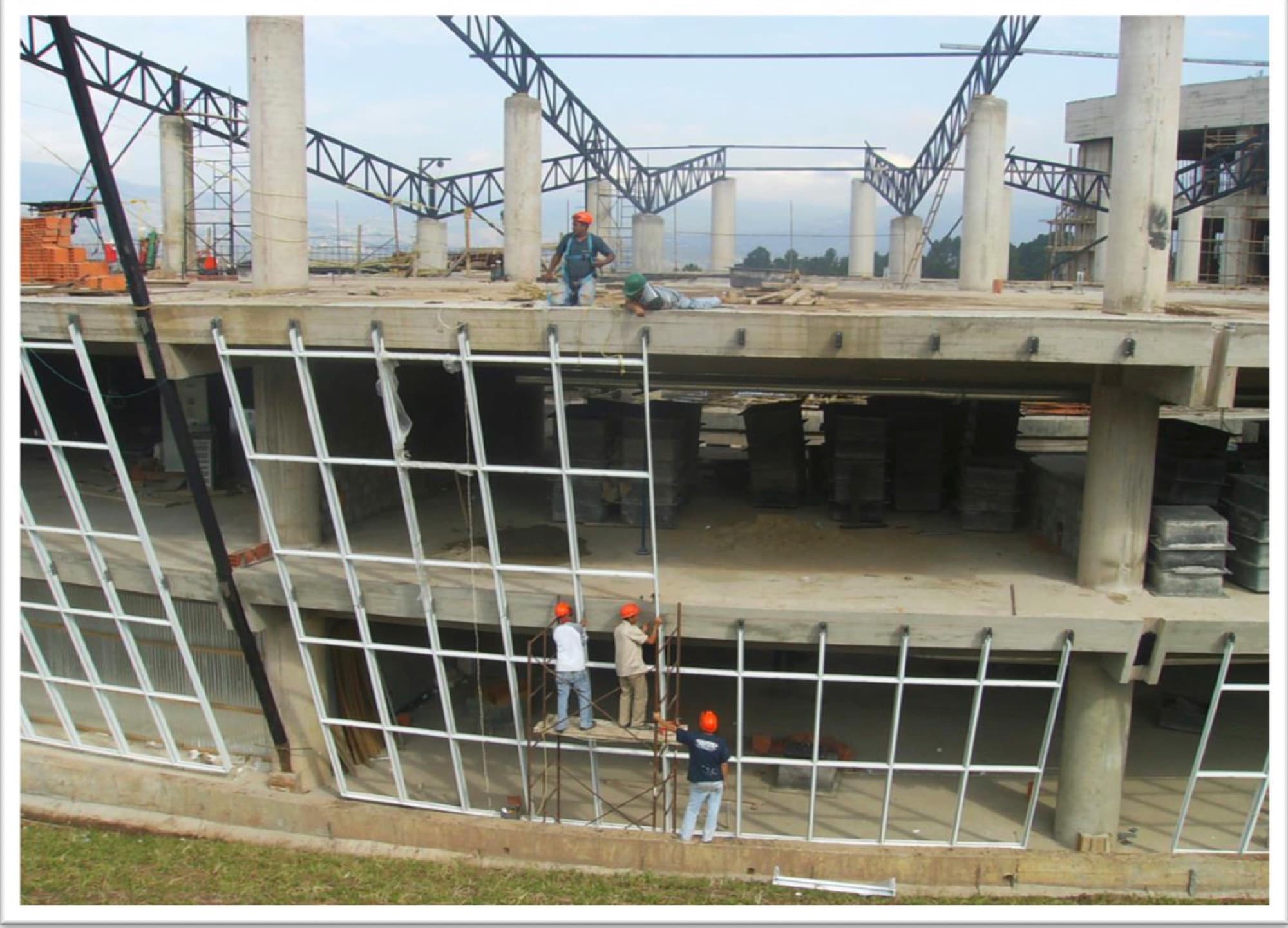 Edificio del SENIAT en construcción, con la estructura de la fachada curva de vidrio y personal en obra
